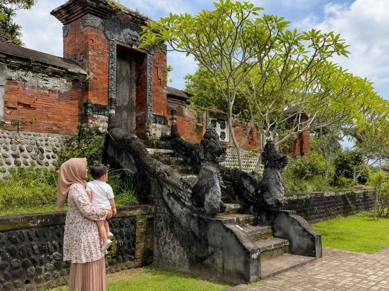 Ibu dan anak melihat bangunan bersejarah serta ukiran batu di Taman Narmada
