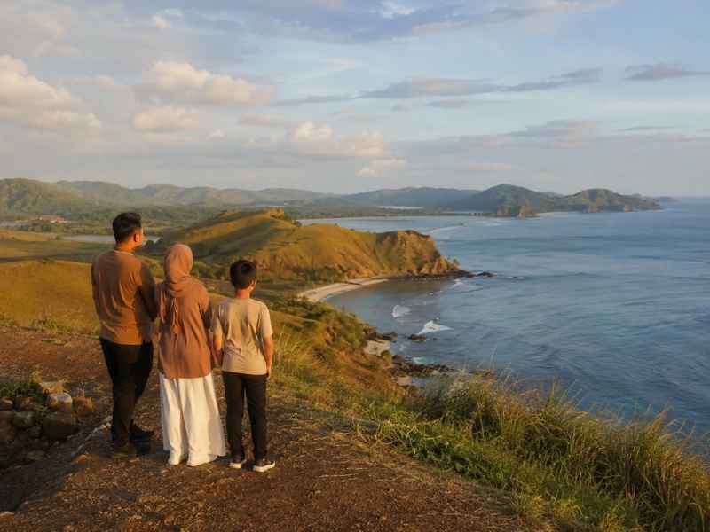 Keluarga menikmati pemandangan laut dari Bukit Merese saat sore hari