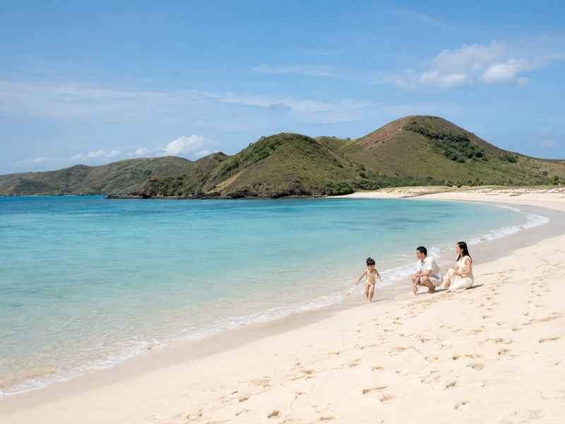 Orang tua dan anak menikmati Pantai Tanjung Aan dalam perjalanan wisata keluarga di Mandalika