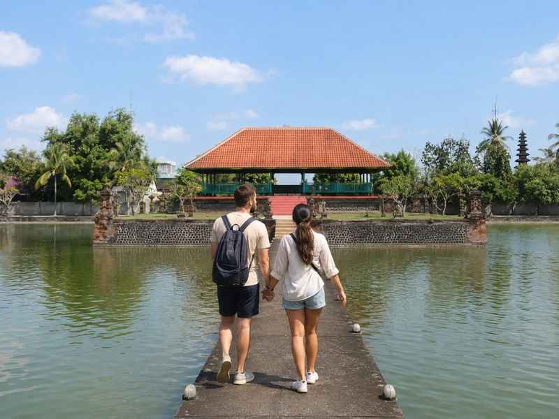 Pasangan wisatawan menuju Bale Kambang di Taman Mayura