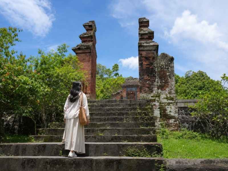 Wisatawan menaiki tangga batu menuju gerbang bersejarah Taman Narmada Lombok