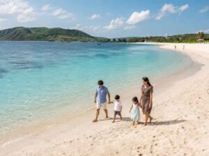 Keluarga berjalan santai di Pantai Kuta Mandalika dengan laut biru dan perbukitan Lombok
